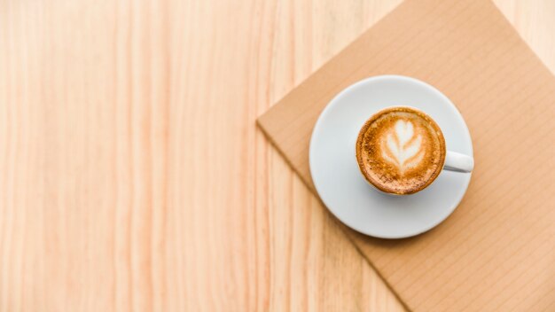 Vista ambientale del latte e del taccuino del caffè sul contesto di legno