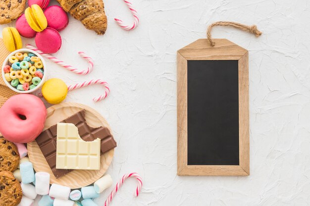 Vista ambientale dell&#39;etichetta di legno dell&#39;ardesia e degli alimenti dolci su fondo bianco