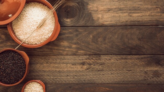 Vista ambientale delle ciotole di grano di riso sano sulla tavola di legno