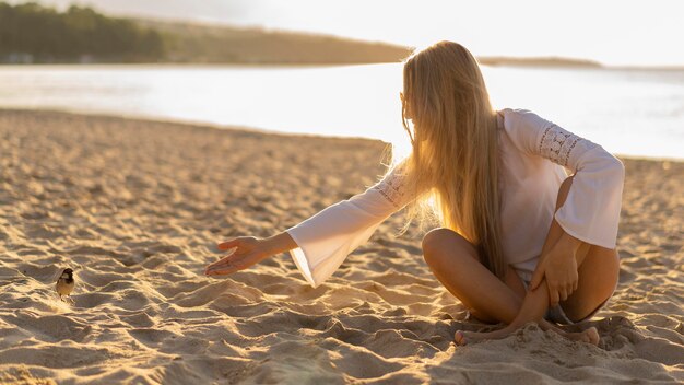 Vista anteriore di una donna sulla spiaggia con un uccello