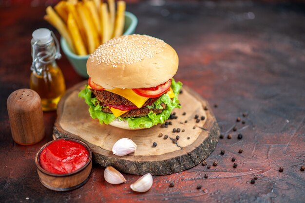 Vista anteriore hamburger di carne gustoso con patatine fritte sullo sfondo scuro