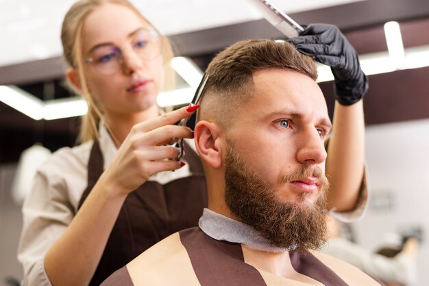 Vista bassa donna che taglia i capelli di un cliente