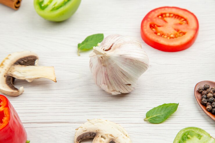 Foto gratuito vista dal basso aglio funghi pomodori verdi e rossi foglie di menta sul tavolo grigio