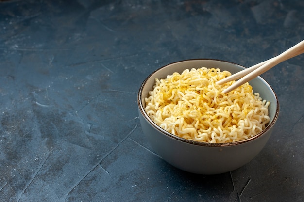 Vista dal basso bacchette di ramen asiatico noodles in una ciotola bianca sul tavolo scuro waribashi