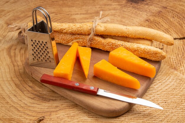 Vista dal basso coltello da pane e formaggio piccola grattugia su tagliere su superficie di legno