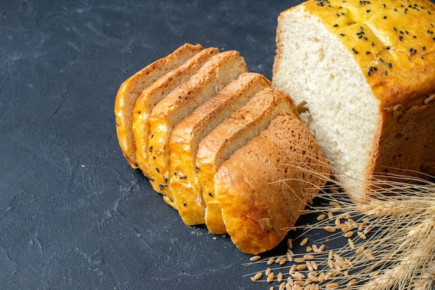 Vista dal basso fette di pane spighe di grano e cereali sullo spazio libero del tavolo scuro