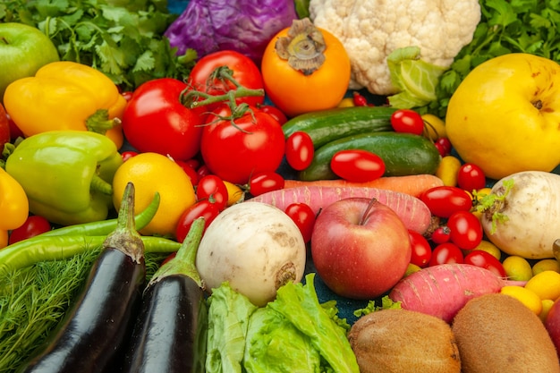 Vista dal basso frutta e verdura ravanello pomodorini cachi pomodori kiwi cetriolo mele cavolo rosso prezzemolo mela cotogna melanzane sul tavolo blu