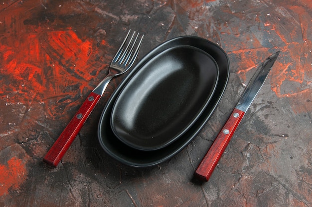 Vista dal basso grandi piccoli piatti forchetta e coltello sul tavolo rosso scuro