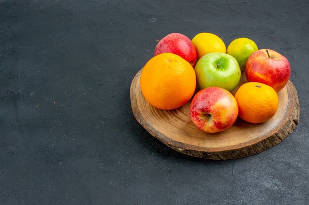 Vista dal basso mele limone arance su tavola di legno su superficie scura posto libero