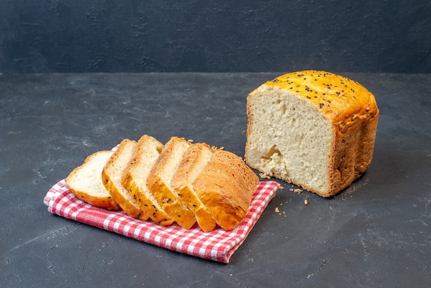 Vista dal basso metà pane e fette di pane su asciugamano da cucina a quadretti rosso e bianco sul tavolo scuro