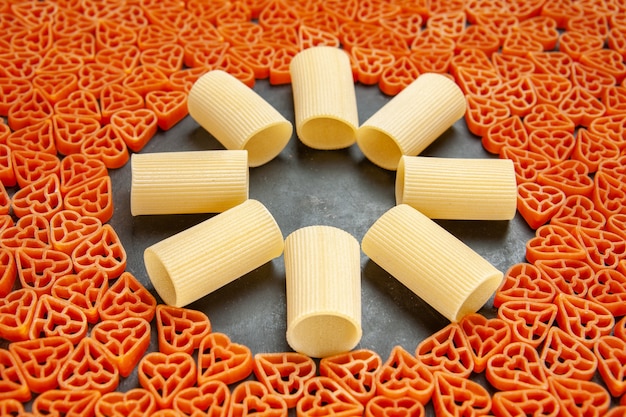 Vista dal basso pasta italiana a forma di cuore e rigatoni su superficie scura dark