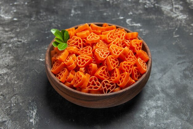 Vista dal basso pasta italiana rossa a forma di cuore in una ciotola su superficie scura