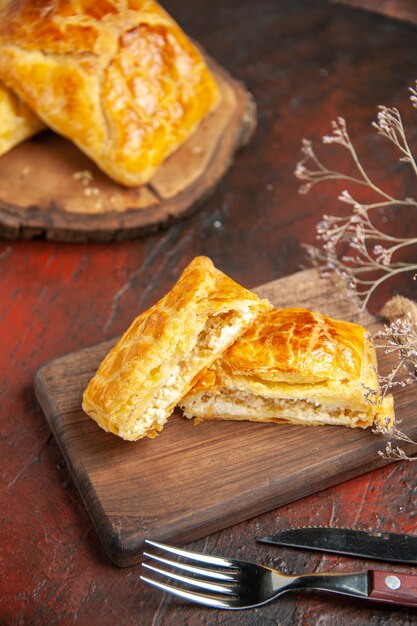 Vista dal basso penovani khachapuri su tavola di legno e su tagliere coltello e forchetta su tavolo rosso scuro