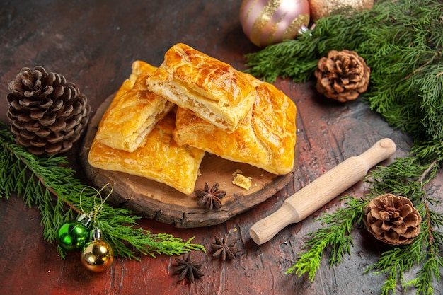 Vista dal basso penovani khachapuri su tavola di legno mattarello pino rami e coni anice stellato giocattoli di natale sul tavolo rosso scuro