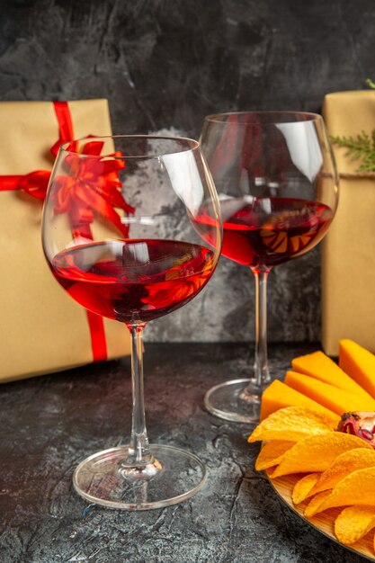 Vista dal basso pezzi di formaggio carne uva e melograno su tavola ovale bicchiere di vino regali di natale al buio