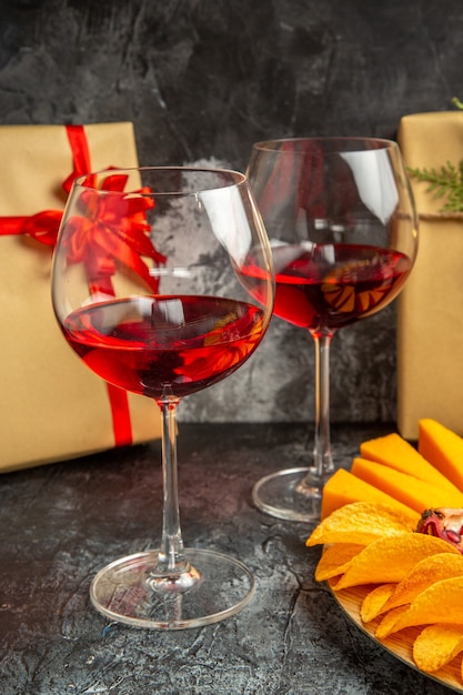 Vista dal basso pezzi di formaggio carne uva e melograno su tavola ovale bicchiere di vino regali di natale al buio