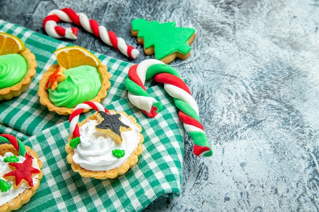 Vista dal basso piccole crostate di natale sulla tovaglia caramelle di natale sullo spazio libero del tavolo grigio