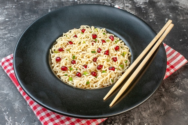 Vista dal basso ramen noodles bacchette su piatto nero tovaglia a quadretti rossa e bianca sul tavolo scuro