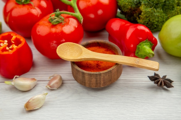 Vista dal basso ramo di pomodoro broccoli anice aglio cucchiai di legno sulla ciotola delle spezie sul tavolo grigio