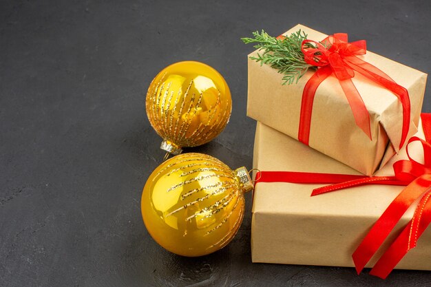 Vista dal basso regali di Natale grandi e piccoli in carta marrone legati con palline di Natale con nastro rosso su sfondo scuro