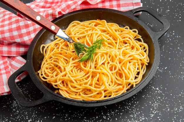 Vista dal basso spaghetti padella tovaglia a quadretti rossa e bianca su sfondo scuro