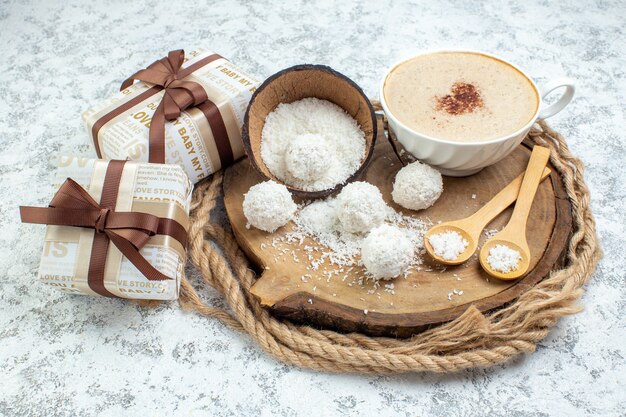 Vista dal basso tazza da cappuccino tazza di polvere di cocco ciotola cucchiai di legno su tavola di legno regali su sfondo grigio