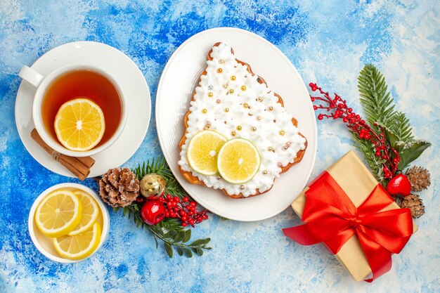 Vista dal basso una tazza di tè con fette di limone torta sul piatto regalo di Natale sul tavolo blu