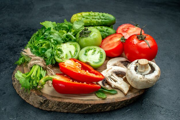 Vista dal basso verdure pomodori peperoni cetrioli verdi funghi su tavola di legno su tavola nera