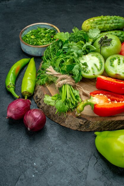 Vista dal basso verdure pomodori peperoni cetrioli verdi su tavola di legno peperoni piccanti cipolle rosse su tavola nera