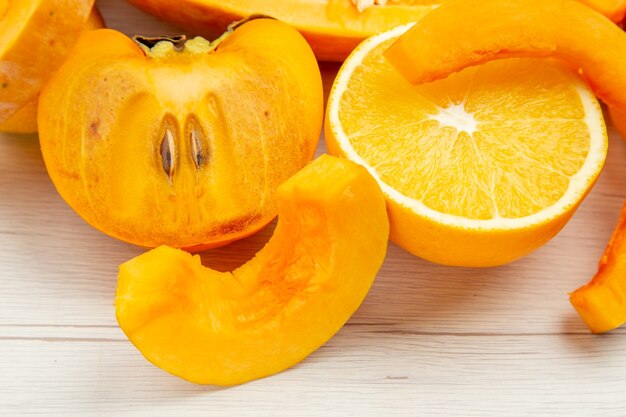 Vista dal basso zucca tagliata cachi arancioni sul tavolo bianco