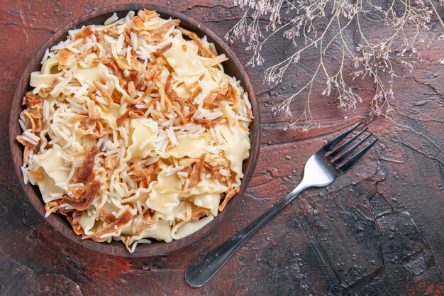 Vista dall'alto a fette di pasta cotta con riso sulla pasta del piatto di pasta del pasto superficie scura