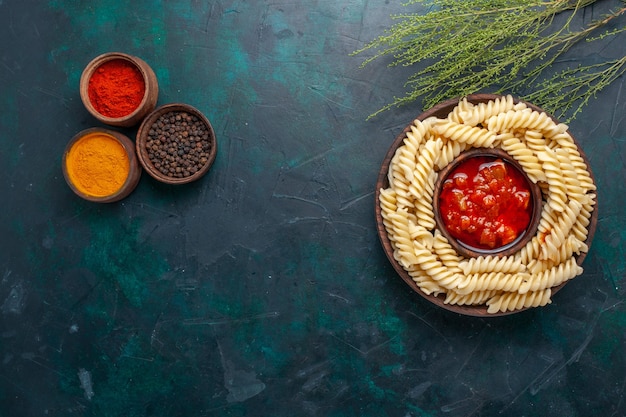 Vista dall'alto a forma di pasta italiana con condimenti sulla scrivania blu scuro