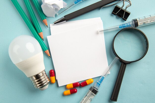 vista dall'alto adesivi bianchi con iniezioni di matite e pillole su sfondo blu laboratorio scienza pandemia ospedale virus pillola covid colore salute