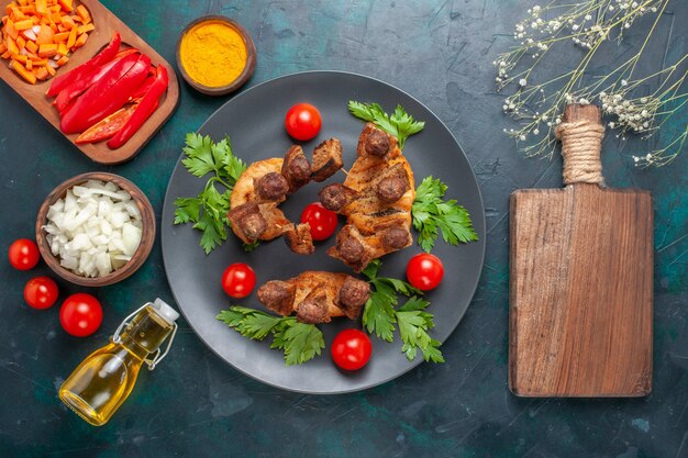 Vista dall'alto affettato di carne cotta con pomodorini verdi e olio d'oliva su sfondo blu