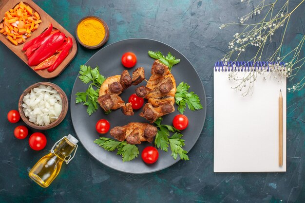 Vista dall'alto affettato di carne cotta con pomodorini verdi e olio d'oliva sulla scrivania blu