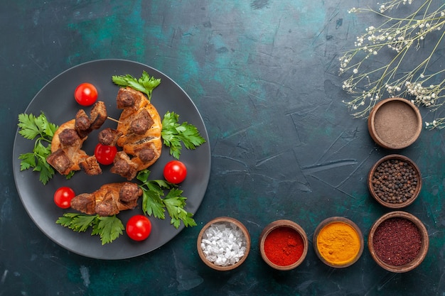 Vista dall'alto affettato di carne cotta con verdure e pomodorini con condimenti su sfondo blu