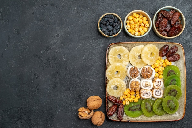 Vista dall'alto affettato frutta secca ananas anelli e kiwi su sfondo grigio frutta secca uvetta dolce vitamina acido salute