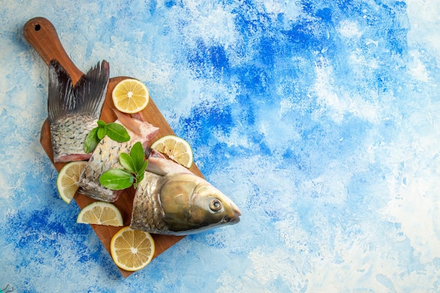 Vista dall'alto affettato pesce fresco con fette di limone sulla superficie blu