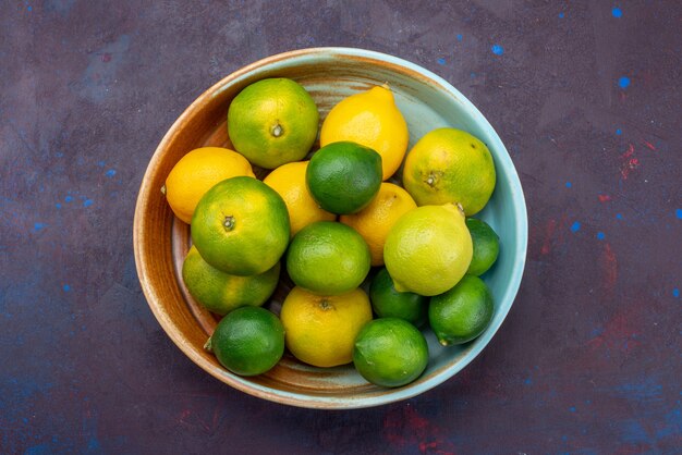 Vista dall'alto agrumi succosi limoni e mandarini sulla scrivania scura agrumi frutta arancione esotica tropicale