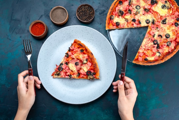 Vista dall'alto al forno deliziosa pizza con olive, salsicce e formaggio sulla scrivania blu.