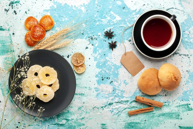 Vista dall'alto anelli di ananas essiccati con piccoli biscotti e tazza di tè su sfondo blu torta cuocere biscotti alla frutta dolce zucchero biscotto