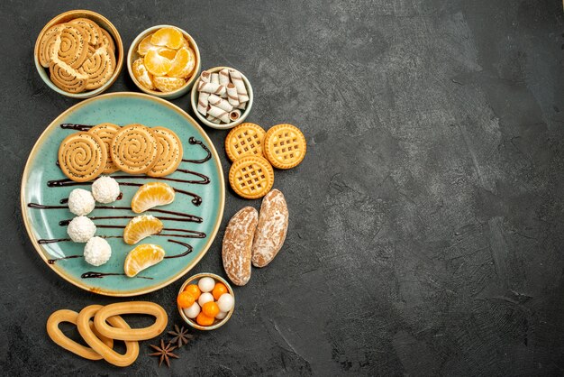 Vista dall'alto biscotti dolci con caramelle e biscotti su sfondo grigio