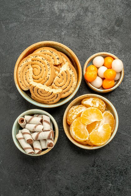 Vista dall'alto biscotti dolci con frutta e caramelle su sfondo scuro