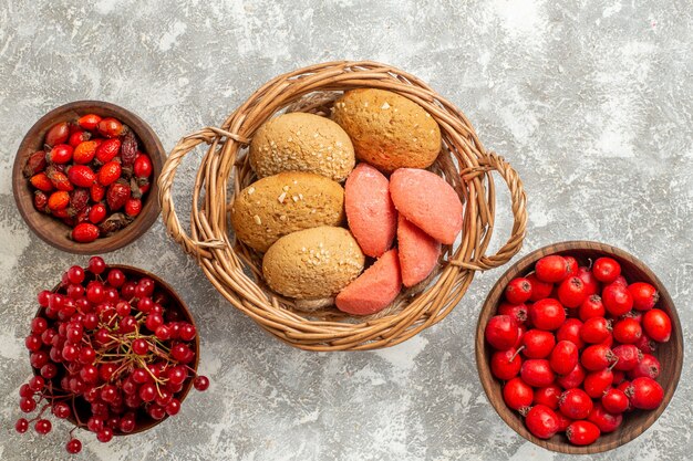 Vista dall'alto biscotti dolci con frutti rossi su sfondo bianco