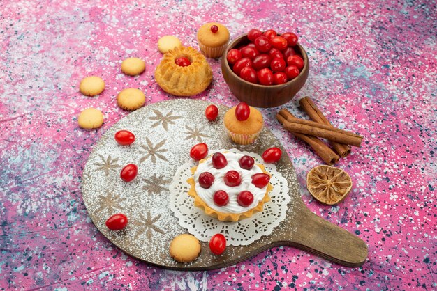 Vista dall'alto biscotti e torte con panna e mirtilli rossi freschi sulla superficie esposta