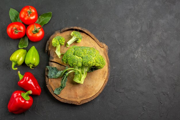 Vista dall'alto broccoli freschi con pomodori e peperoni su insalata matura tavolo scuro