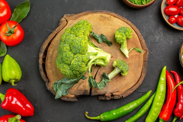 Vista dall'alto broccoli freschi con pomodori e peperoni sul colore insalata matura tavolo scuro
