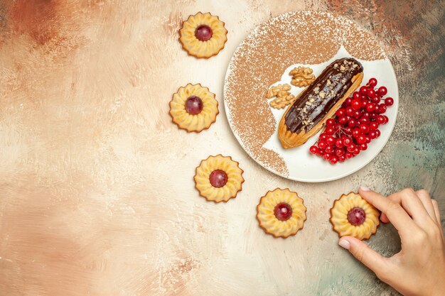 Vista dall'alto buonissimo eclair con bacche rosse e biscotti sul dolce da dessert torta tavolo leggero