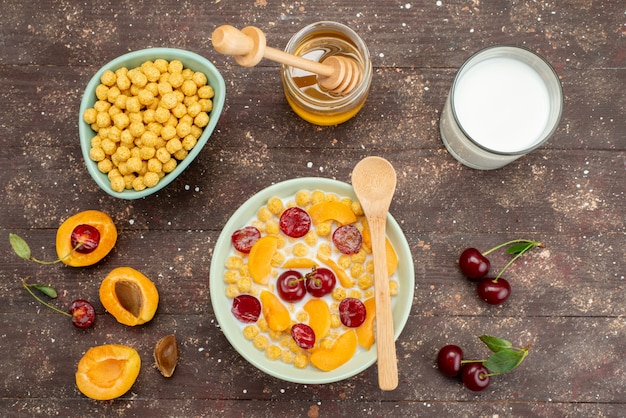 Vista dall'alto cereali con latte all'interno del piatto con frutta fresca e miele su legno, cereali cereali colazione