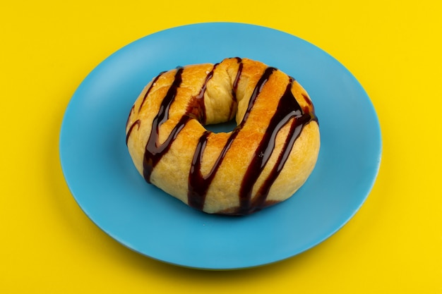 vista dall'alto ciambella con cioccolato all'interno del piatto blu sul giallo